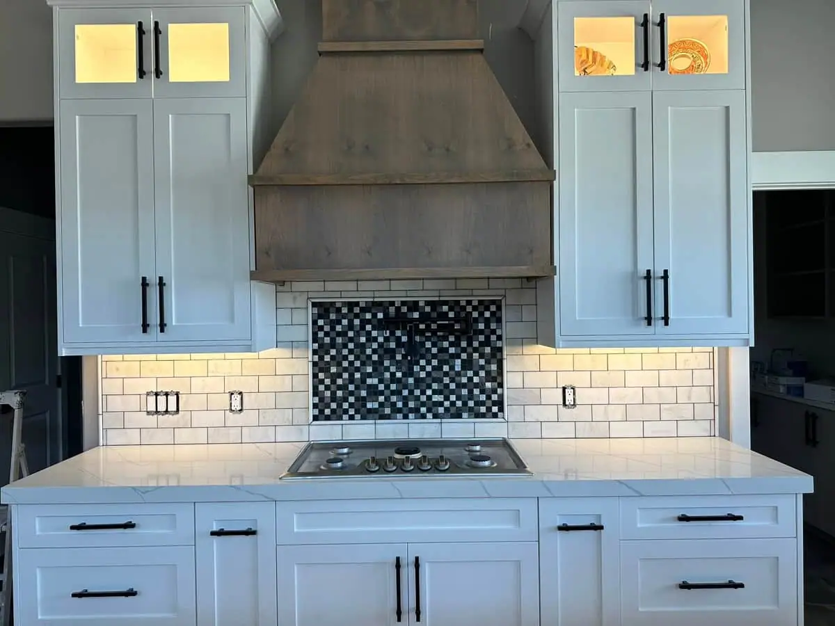 Range hood with subway tile and mosaic accent over a gas cooktop