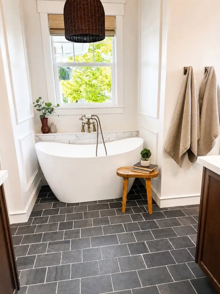 Freestanding tub on a slate tile floor under a picture window
