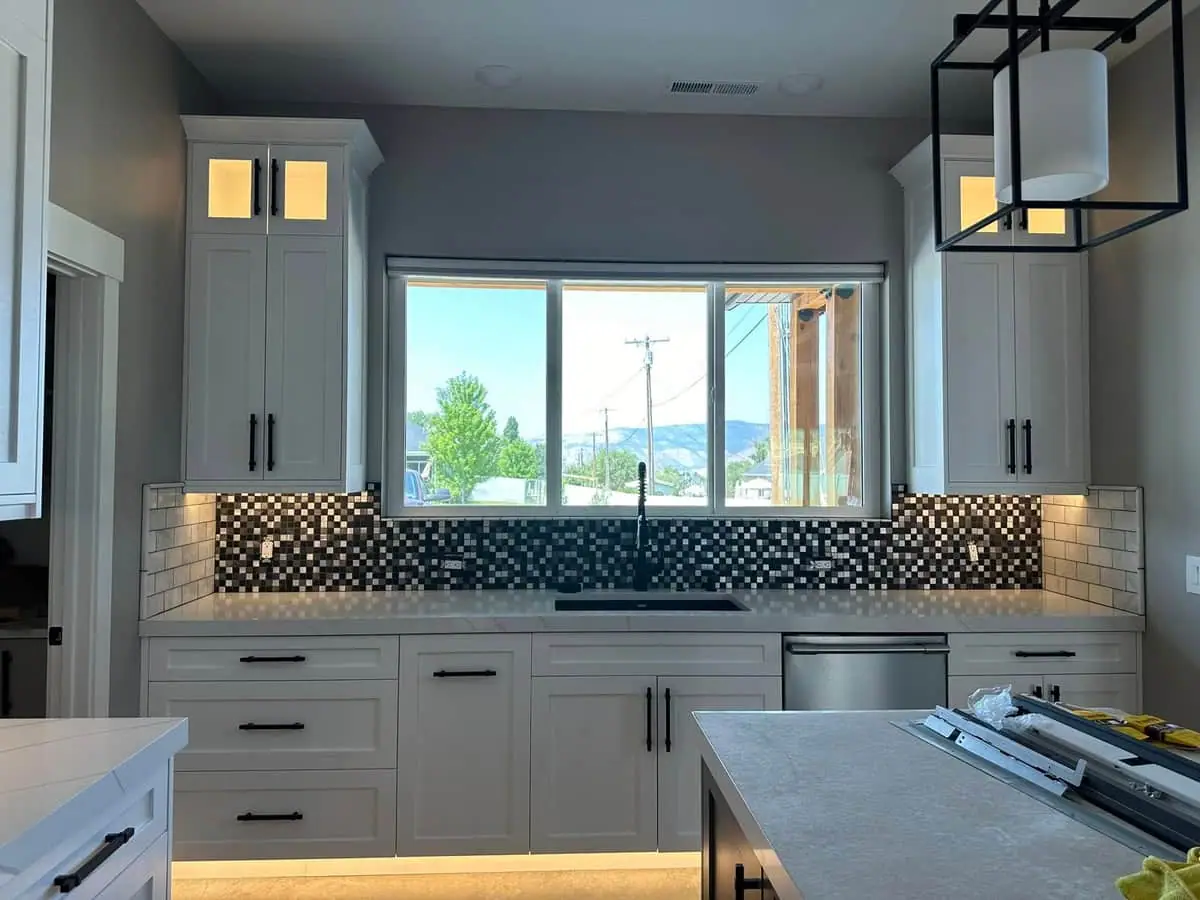 White kitchen with quartz counters, mosaic backsplash, and a valley view
