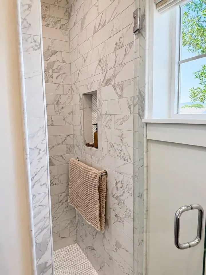 Carrara marble shower with recessed niche and penny-tile floor