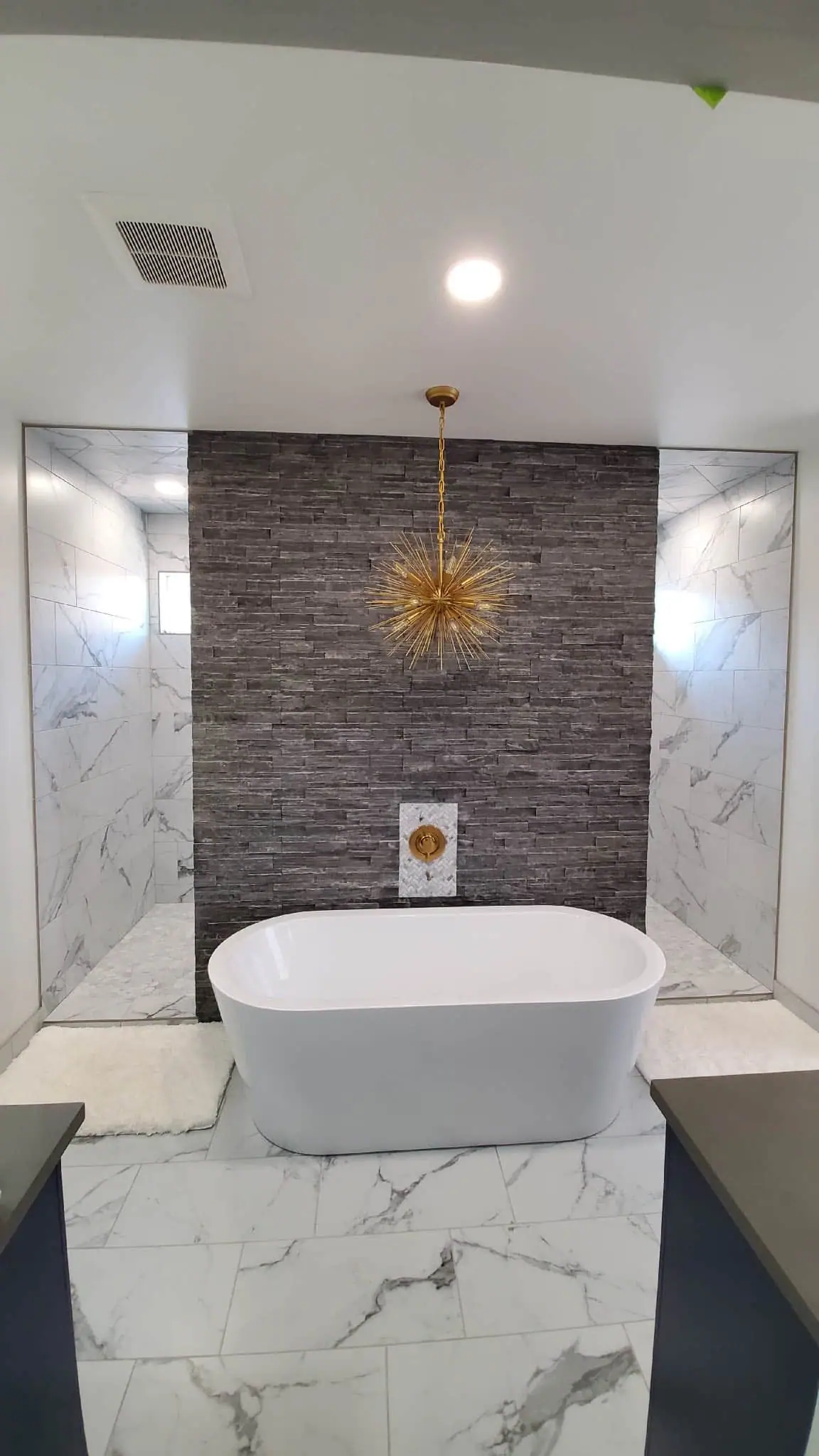 Freestanding soaking tub with marble feature wall and gold chandelier