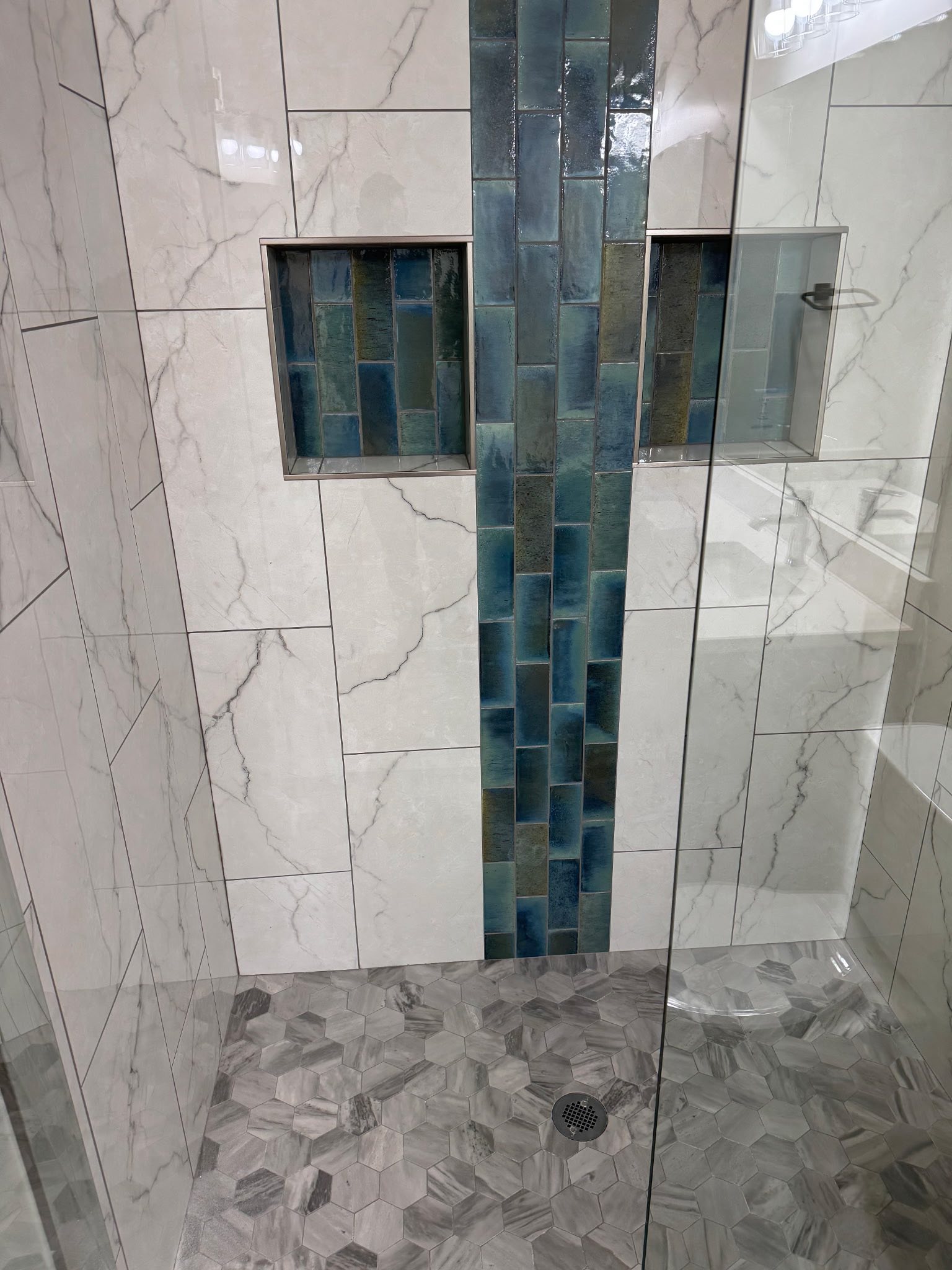 Marble shower with a blue glass accent strip